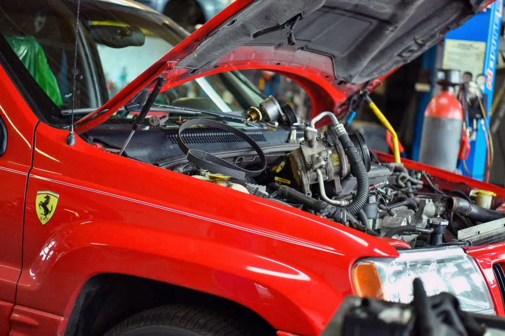 Czerwony Jeep Grand Cherokee II z otwartą maską w warsztacie
